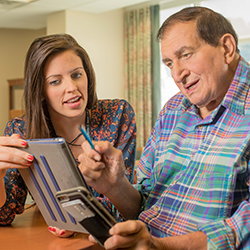 resident and staff looking at a tablet